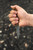 (Forward Grip - Downward Point) Hand holding TOPS El Pionero in forward grip blade-down position | Tan Micarta handle with visible lanyard hole | 1095 carbon steel tactical paring knife in hand