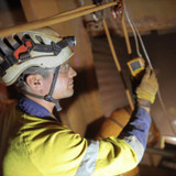 Man wearing a white hardhat, gloves and safety glasses conducting work in a confined space.