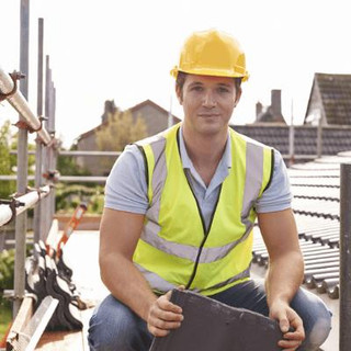 Man installing tiles to a roof, wearing a hardhat and high vis vest.