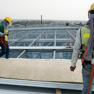 men working on a roof with a safety harness and PPE.