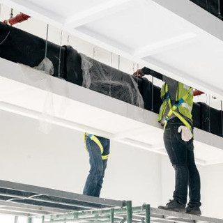 Men standing on a platform installing duct air-conditioning