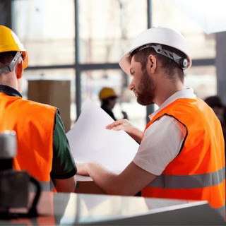 Two men in hardhats and high vis vests looking at documents