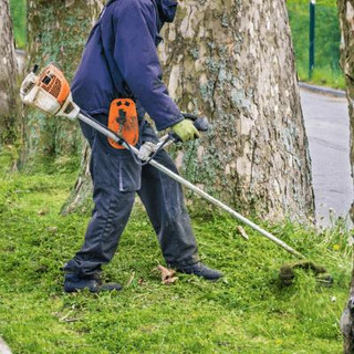 Man using a brush cutter on lawn