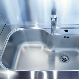 Looking down on an empty stainless steel sink, with stainless steel splashback