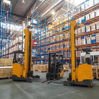A large filled warehouse with 3 forklifts in a semi circle formation.