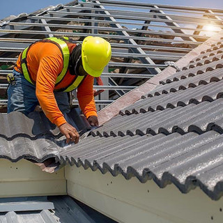 Roof repair, worker replacing grey tiles or shingles on house