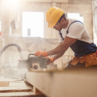 Male builder using wood cutting circular saw machine in workshop