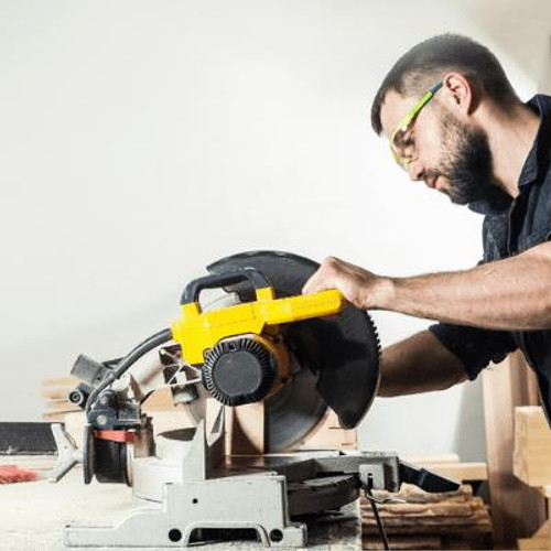 Person wearing safety glasses while using a drop saw to cut timber