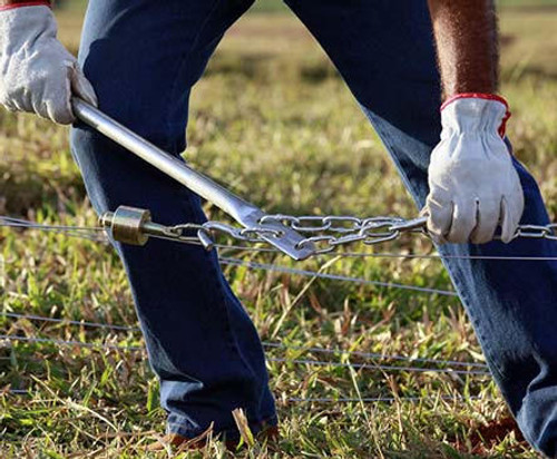 Man wearing protective gloves working on an electric fence.