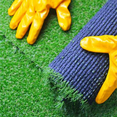 Person wearing yellow gloves unrolling synthetic grass.