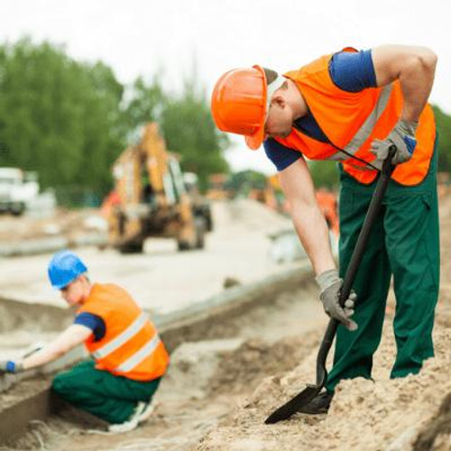 Man wearing a hardhat digging on building site