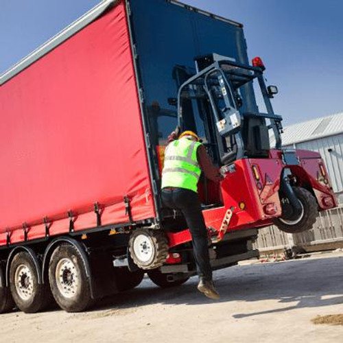 Red truck with a worker standing on the tailgate of truck reaching up to a forklift mounted at the rear of truck.