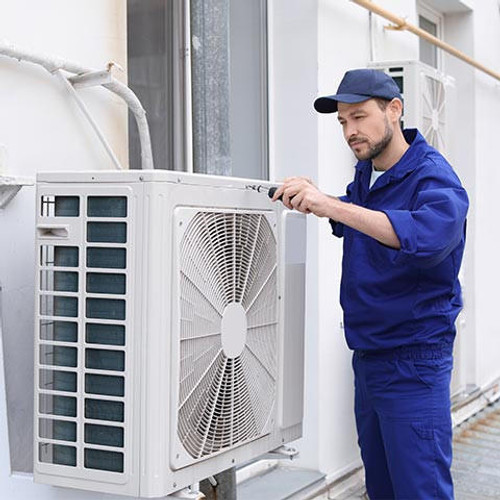Male technician repairing air conditioner outdoors