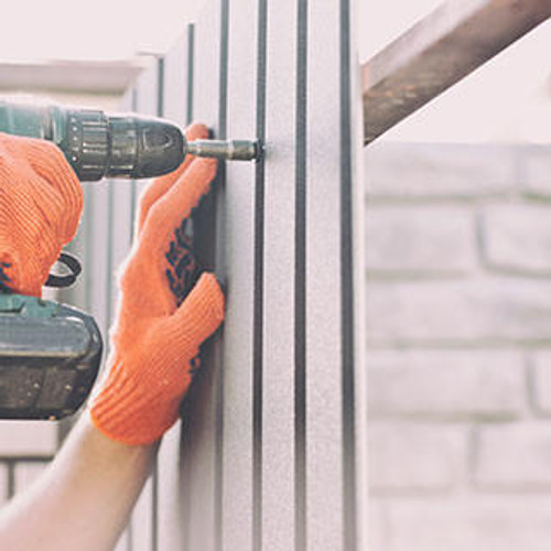 Worker screwing screw into metal fence