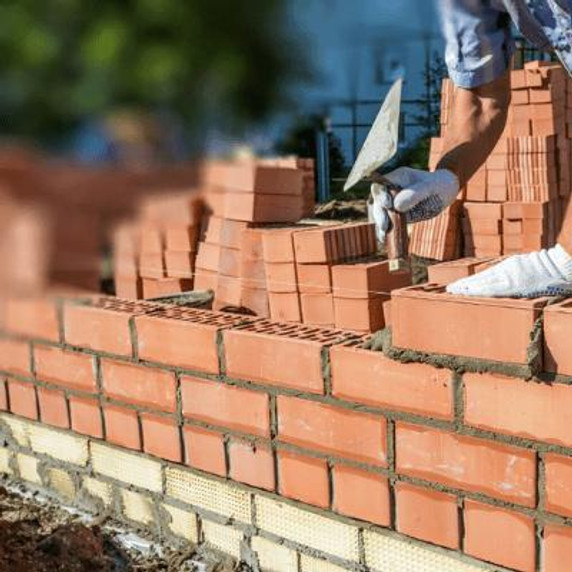 Red bricks being positioned to create a wall, person laying them into position