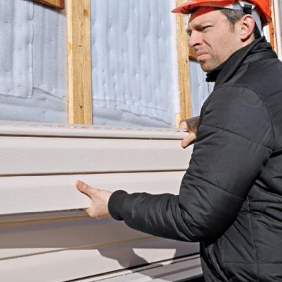 Man wearing a red hardhat and long sleeve jumper applying cladding