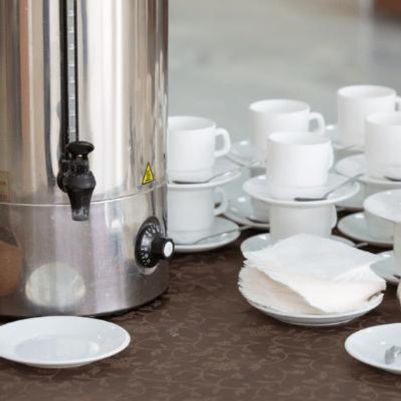 Hot water urn on table with cups and saucers