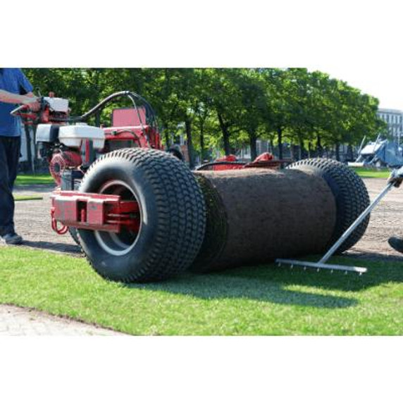 Two people laying maxi rolls of turf using a machine.