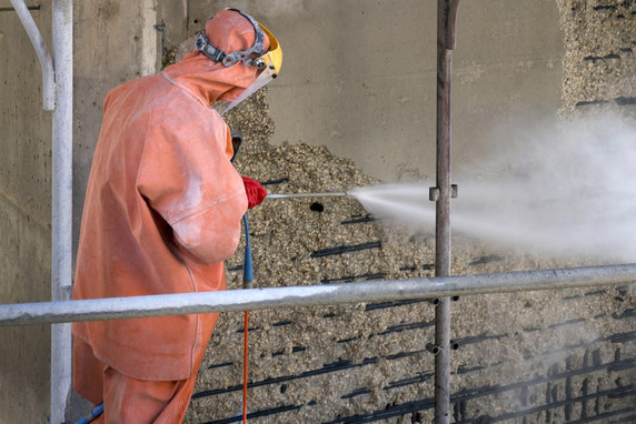 Man in orange protective suit, face shield, removing concrete using an ultra high-pressure cleaner