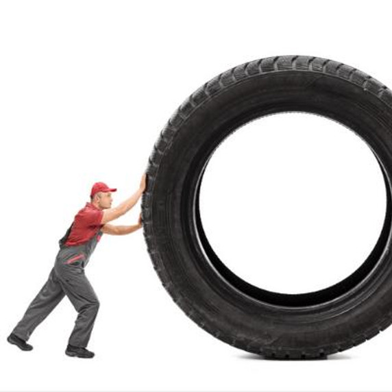 Man pushing a large tyre.