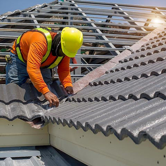 Roof repair, worker replacing grey tiles or shingles on house