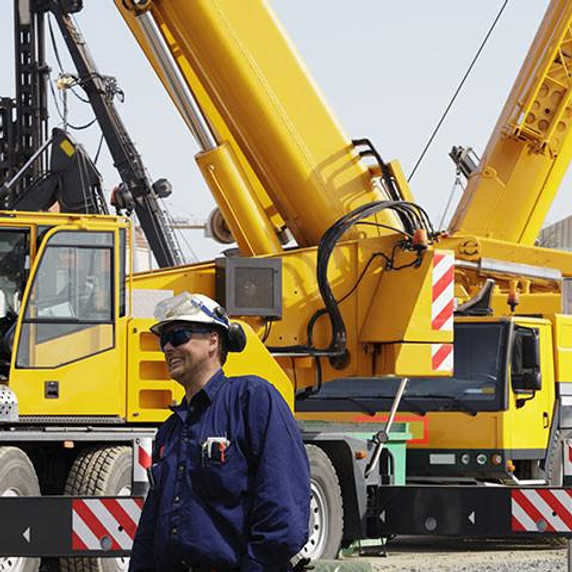 Construction workers with giant mobile cranes in background