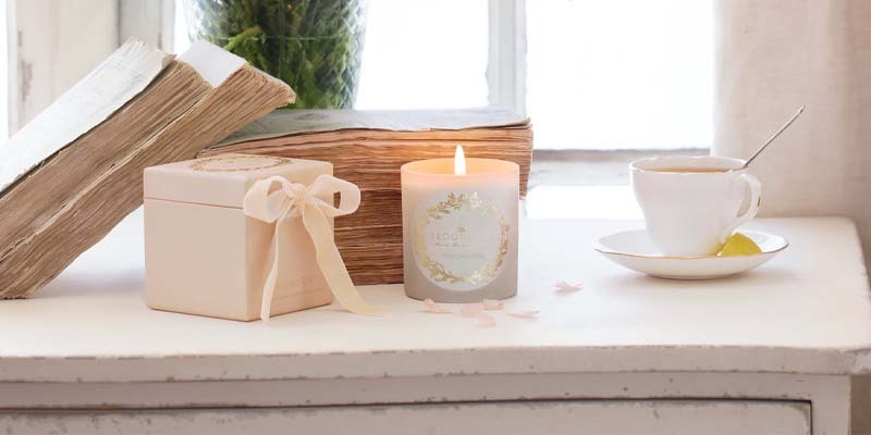 A candle, book, cup, and saucer on a table