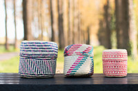 Two medium and one small colourful handwoven baskets on a picnic bench