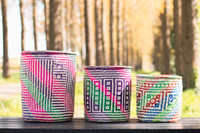 Three large colourful handwoven baskets on a picnic bench