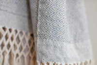 Close-up of Silver Moonlight Serenity Oaxacan Shawl showcasing soft grey and white blend and intricate handwoven pattern. Experience the craftsmanship of the Silver Moonlight Serenity Oaxacan Shawl. This handwoven marvel features a unique grey and white pattern, adding a touch of sophistication to any wardrobe.