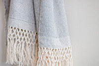 Silver Moonlight Serenity Oaxacan Shawl worn as a statement piece with intricate weaving details highlighted. Make a statement with the Silver Moonlight Serenity Oaxacan Shawl. This handwoven masterpiece features a captivating blend of soft grey and white, perfect for adding timeless elegance to your style.