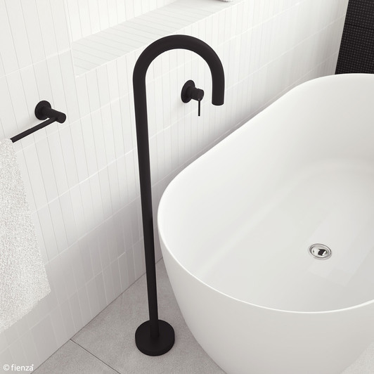 Product image of the Hustle Floor Mounted Bath Outlet in matte black. A round, floor mounted hook spout with solid round base. Pictured with a freestanding bath, view from above.
