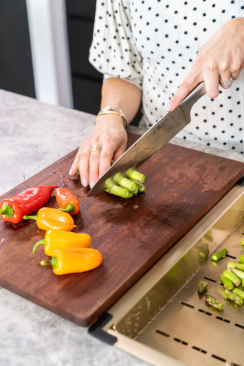 Person chopping vegetables on the Lavello Chopping Board
