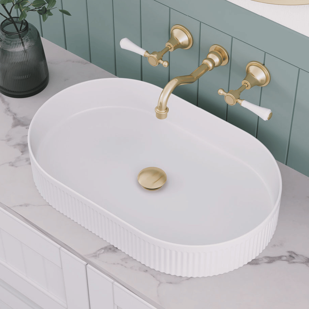 Fluted oval, above counter basin on a marble top vanity with urban brass wall mounted lever tap set.