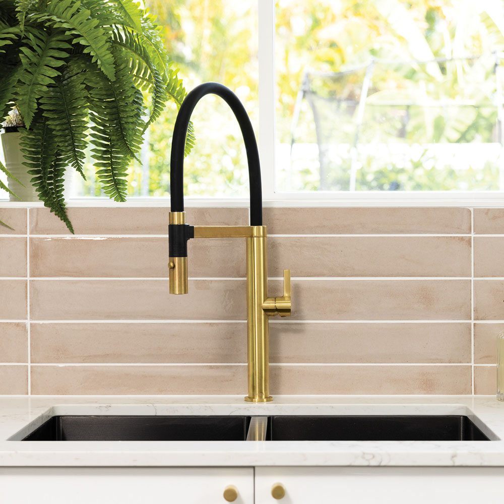 Industrial style kitchen sink mixer. The hose is black and the body of the tap is brass.