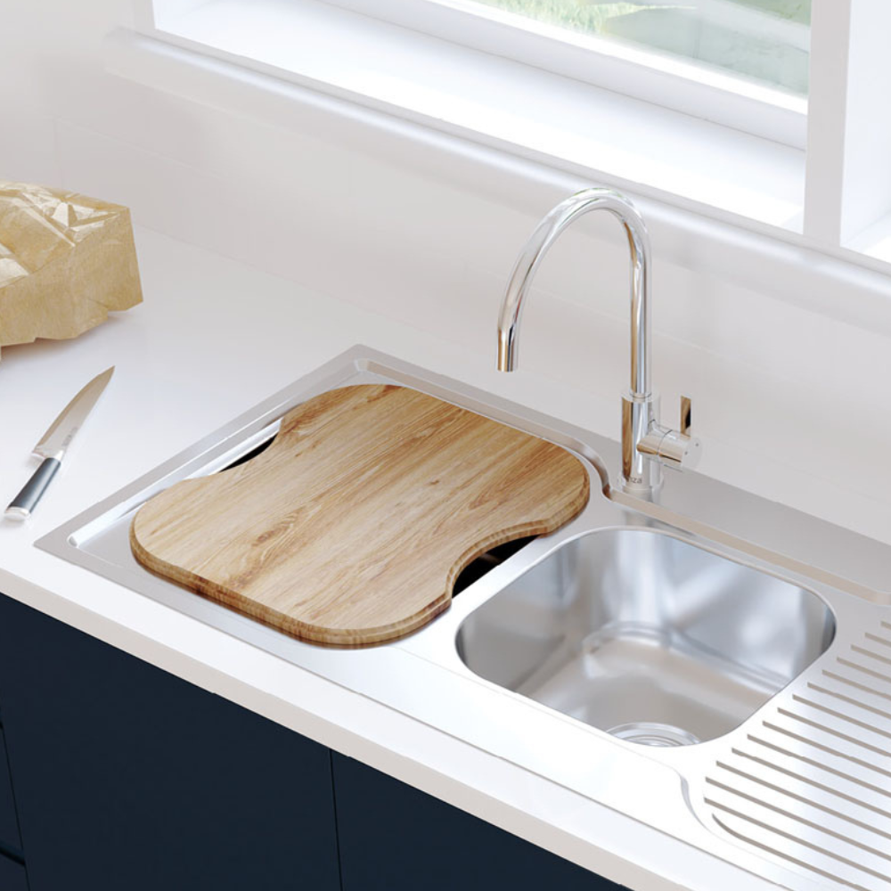 A wooden chopping board that fits snuggly above the large bowl of a twin kitchen sink.