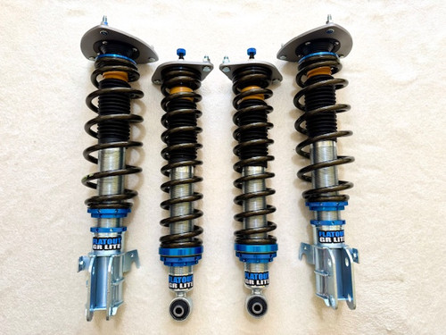 Flatout GR Lite coilovers set for Subaru vehicles, featuring four complete shock and spring assemblies with blue anodized hardware, linear springs, and upright rebuildable shocks