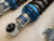 Flatout GR Lite coilovers set for Subaru vehicles, featuring four complete shock and spring assemblies with blue anodized hardware, linear springs, and upright rebuildable shocks