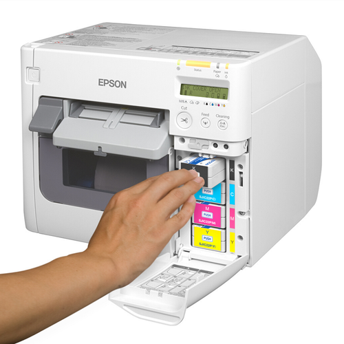 A person's hand inserting an ink cartridge into the front panel of an Epson ColorWorks label printer