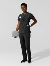 A full body matching top and pant view of a  female healthcare worker wearing the Carhartt chest pocket scrub top C13810 in black