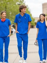 Two female and one male healthcare workers walking on a college campus walkway wearing Spirit Scrubs in royal blue.