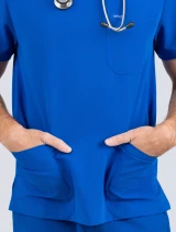 Zoomed image of the front pockets with a male's hands in them  of the Spirit Scrubs men's 3-pocket V-neck scrub top in royal blue (style #UOT336)