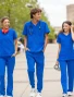 Two female and one male healthcare workers walking on a college campus walkway wearing Spirit Scrubs in royal blue.