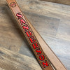 Brown radio strap with red paint, black outline and black stitching