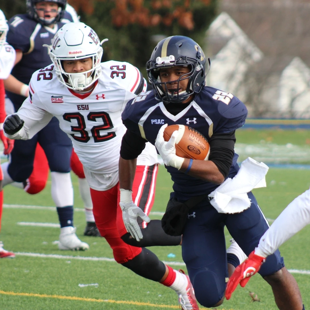 An NCAA Running Back breaking through defenders during an NCAA football game.