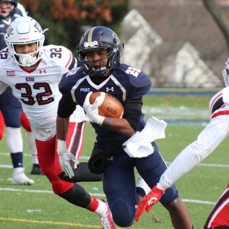 A college football player running between  multiple defenders
