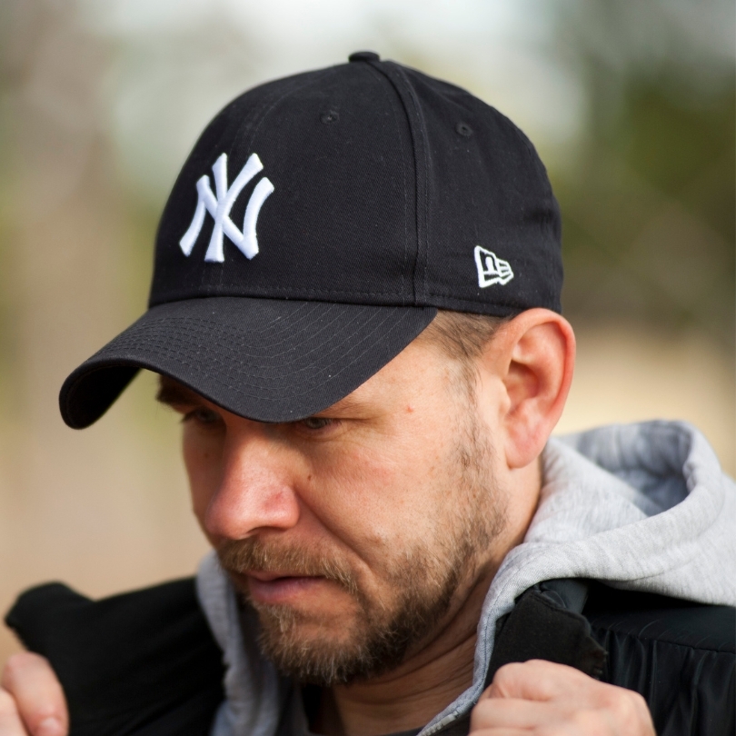 A man wearing a black new york yankees baseball cap