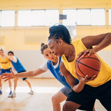 Two women playing basketball on a basketball court