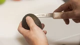 S104SC, 15373, 3 ¼" Scalloped Parer cutting into an avocado on a white cutting board