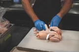 boning knife cutting through a whole chicken